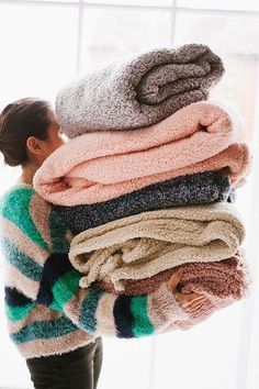 a woman is holding a stack of towels