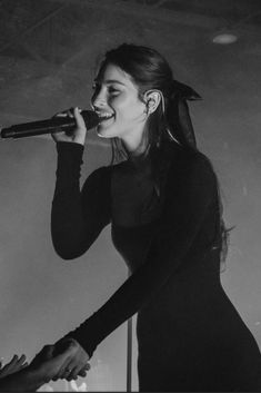 a black and white photo of a woman singing into a microphone