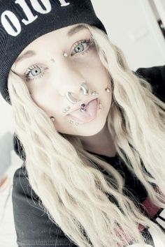 a woman with piercings on her nose wearing a beanie