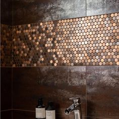 a bathroom sink with soap and lotion on the counter next to it, in front of a tiled wall