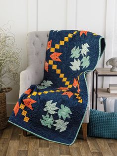 a chair with a quilt on it next to a potted plant and a basket