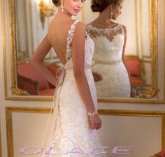 a woman in a wedding dress looking at herself in the mirror with her hand on her hip