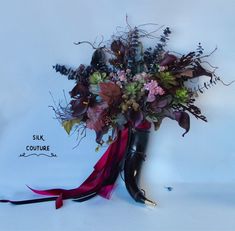 a vase filled with lots of flowers on top of a white table next to a ribbon