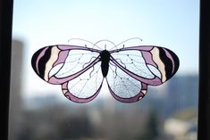 a close up of a window with a butterfly on it's glass and buildings in the background