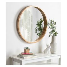 a round mirror sitting on top of a white table next to a potted plant