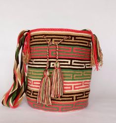 a multicolored bag with tassels and fringe on the handle is sitting against a white background