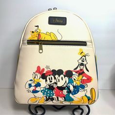 Nwt. Loungefly Disney Mini Backpack Of The Sensational Six (Mickey, Minnie, Donald, Daisy, Goofey, And Pluto). This Bag Is Made Of Vegan Leather (Polyurethane). Cram Color Exterior. Bag Has Adjustable Shoulder Straps, Sturdy Metal Hardware, And Features: Zipper Closure And Printed Details. Interior Is Lined In Yellow Material. Interior Slide Pocket And Exterior Zip Pocket. Bag Dimensions: 9" W X 10" H X 4.5" D (Please Note: Width Is Measured Across The Bottom Of The Bag.) White Backpack For Disney Trips And Back To School, White Mickey Mouse Backpack For Travel, White Mickey Mouse Travel Backpack, Disney Yellow Bags For Everyday Use, Disney Yellow School Bag, Yellow Disney School Bag, Fun White Travel Backpack, White Mickey Mouse Backpack For Disney Trips, Multicolor Mickey Mouse Backpack