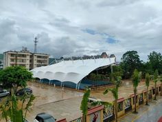 a large white tent sitting in the middle of a parking lot next to tall buildings