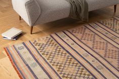 a couch sitting on top of a wooden floor next to a rug and a book