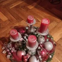 two red candles sitting on top of a wooden floor next to christmas balls and ornaments