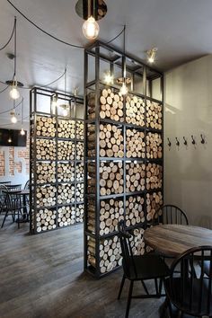 a room with tables, chairs and lots of logs on the wall behind it is a display of wood slices