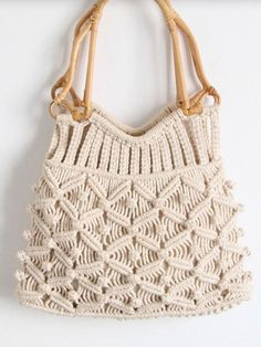 a white crocheted bag hanging on a wooden hook with some hooks attached to it