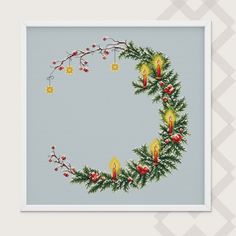 a cross stitch christmas wreath with lit candles