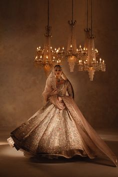 a woman in a wedding dress standing under a chandelier