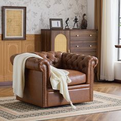 a brown leather chair sitting on top of a hard wood floor next to a window