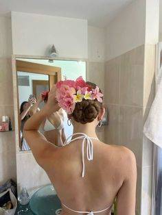 a woman with flowers in her hair standing in front of a bathroom mirror