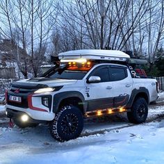 a white truck with lights on driving through the snow