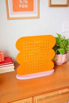 an orange plastic object sitting on top of a wooden table next to a potted plant