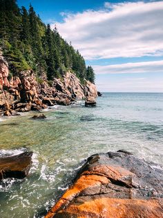 the water is crystal clear and blue with rocks in front of it, along with pine trees on both sides