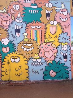 a colorful wall painted with cartoon characters on it's face and mouth, in front of a building