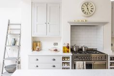 a kitchen with white cabinets and a large clock above the stove