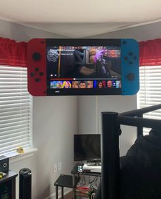 a video game controller hanging from the ceiling above a bed in a room with red curtains