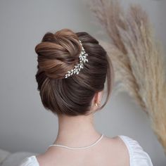 a woman wearing a wedding hair comb with pearls