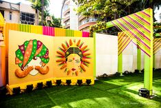 an outdoor area with grass and colorful art on the walls, including two large banners