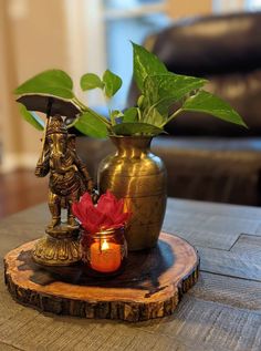 a vase with a plant in it sitting on top of a wooden table next to a candle