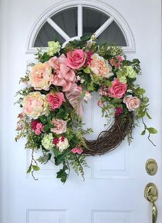 a wreath with pink and white flowers is hanging on the door to a front door