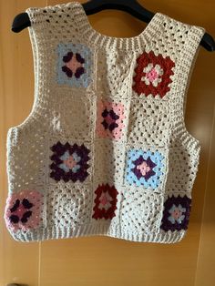 a crocheted vest hanging on a wooden wall