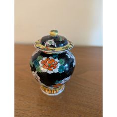 a black and orange vase sitting on top of a wooden table