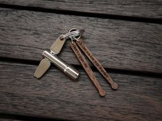 three wooden spoons and two metal tongs sitting on top of a wooden table