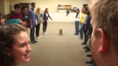 a group of people standing in a room with one woman talking to the other man