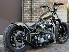 a gold motorcycle parked on top of a brick road next to a building with a door