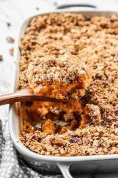 a casserole dish filled with crumbs and topped with a wooden spoon