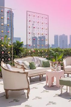 an outdoor seating area with chairs, tables and stools on the roof terrace in front of large cityscape