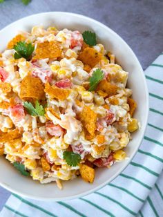 a white bowl filled with macaroni salad and garnished with cilantro