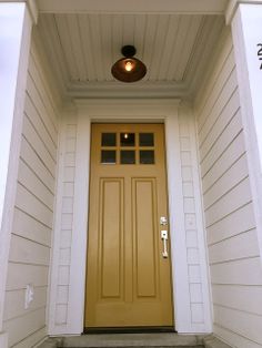 a yellow front door on a white house