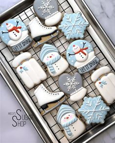 cookies decorated with frosting and snowmen are on a cooling rack in the shape of ice skates