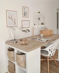 a desk with some baskets and pictures on the wall above it, along with two chairs