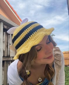 a woman wearing a yellow and black striped crochet hat with ear rings on her head