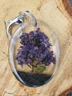 a small purple flower in a clear glass ball on a wooden table with a keychain