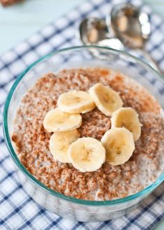 a glass bowl filled with oatmeal and banana slices next to a spoon