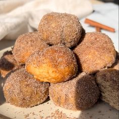 some sugared doughnuts are on a plate with cinnamon sticks in the background