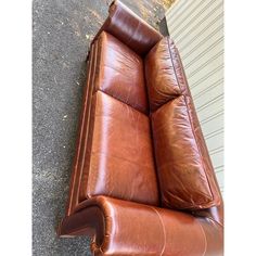 a brown leather couch sitting on top of a sidewalk