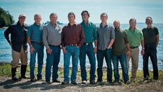 a group of men standing next to each other in front of a body of water