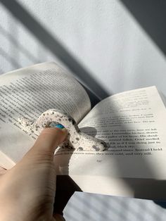 a person holding an open book in their left hand and pointing it at the page