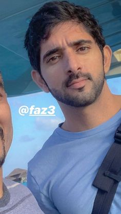 two men standing next to each other in front of a blue umbrella with the word faze on it