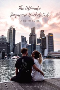 two people sitting on a dock looking at the city skyline with text overlay that reads, the ultimate singapore bucket list a go to guide